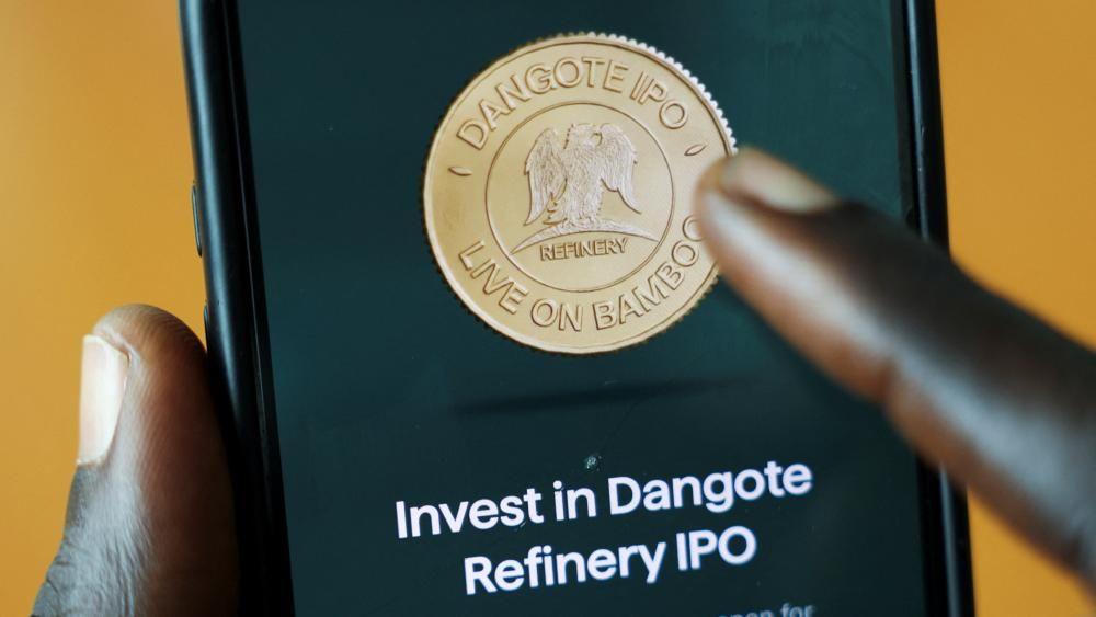 Primer plano de la pantalla de un teléfono con el logotipo de Bamboo y las palabras "Invierta en la salida a bolsa de la refinería Dangote".