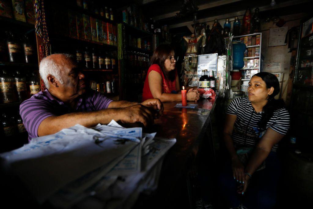 Tres venezolanos dentro de una tienda a oscuras durante un apagón en Venezuela en 2024.