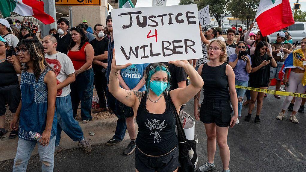 Una manifestante sostiene un cartel que reclama justicia por Wilber Rafael Garcés Pérez. 