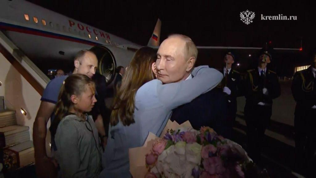 Vladimir Putin, con un ramo de flores en la mano, abraza a una mujer.
