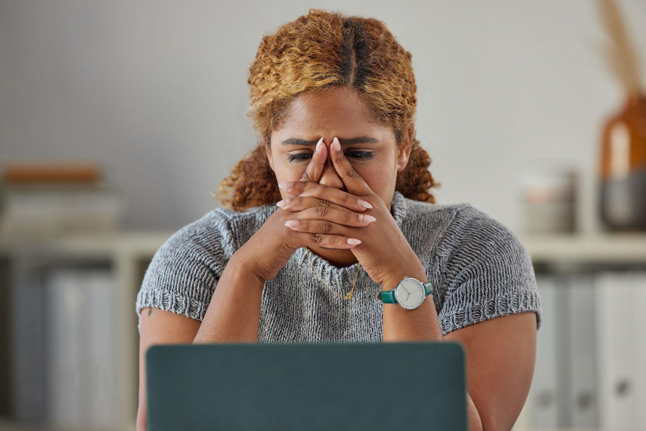 Una mujer mira con tristeza una computadora