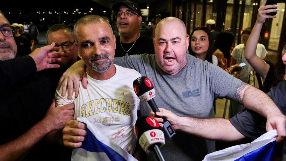 Yaniv Hayun es abrazado por otro hombre mientras los periodistas acercan sus micrófonos 
