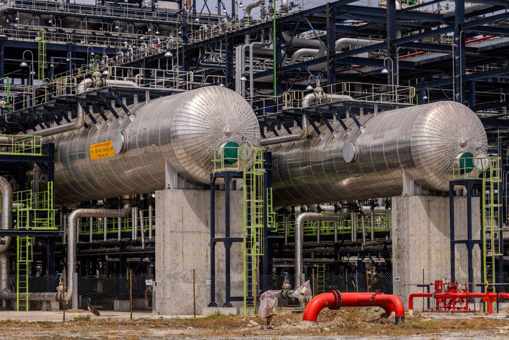 Tanques de petróleo en la refinería y planta de fertilizantes de Dangote Industries Ltd., ubicada en el distrito de Ibeju Lekki, Lagos, Nigeria. Los enormes tanques metálicos están rodeados de una estructura verde.