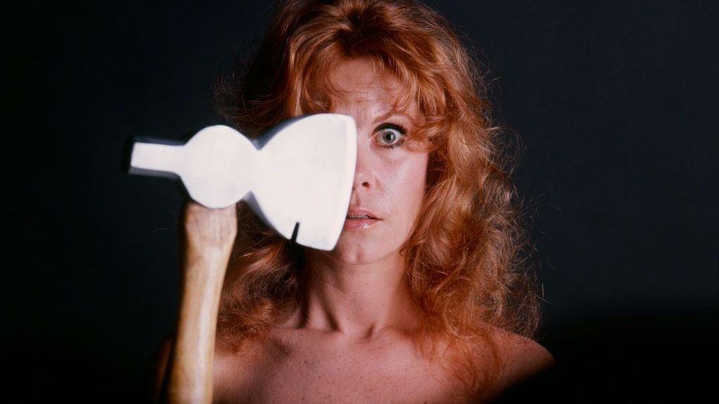 Una foto promocional de la película de TV "La leyenda de Lizzie Borden" con Elizabeth Montgomery sosteniendo un hacha que le cubre mitad de la cara, sobre un fondo negro