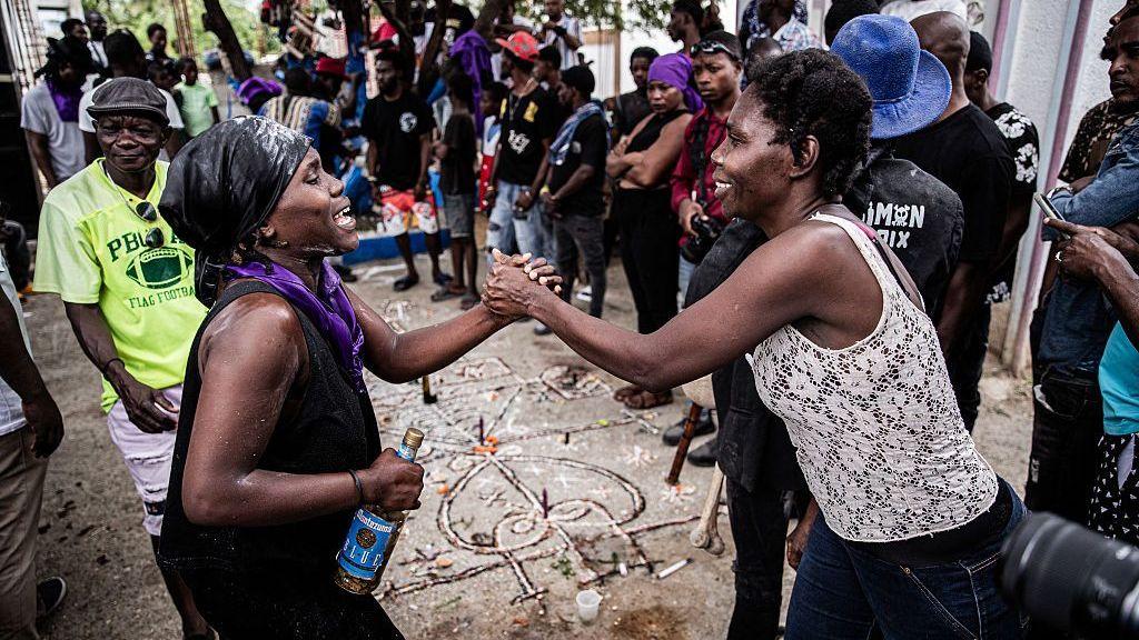 Dos mujeres se toman de la mano durante el festival de los muertos que se celebra en Haití.