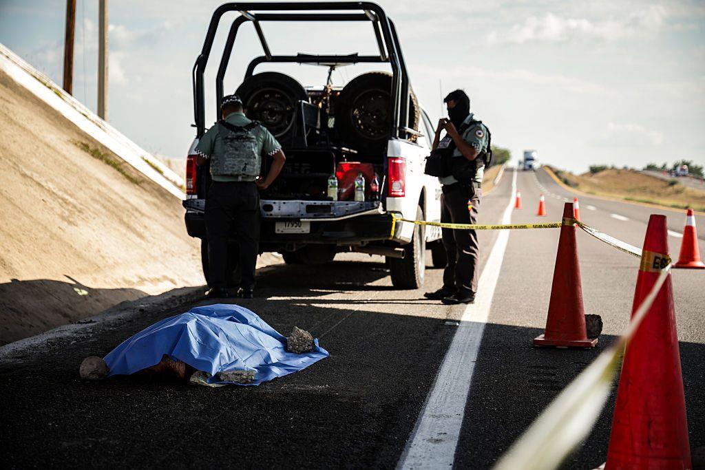 Fuerzas de seguridad cerca de un cadáver cubierto con signos de violencia hallado en una carretera de Sinaloa en enero de 2026