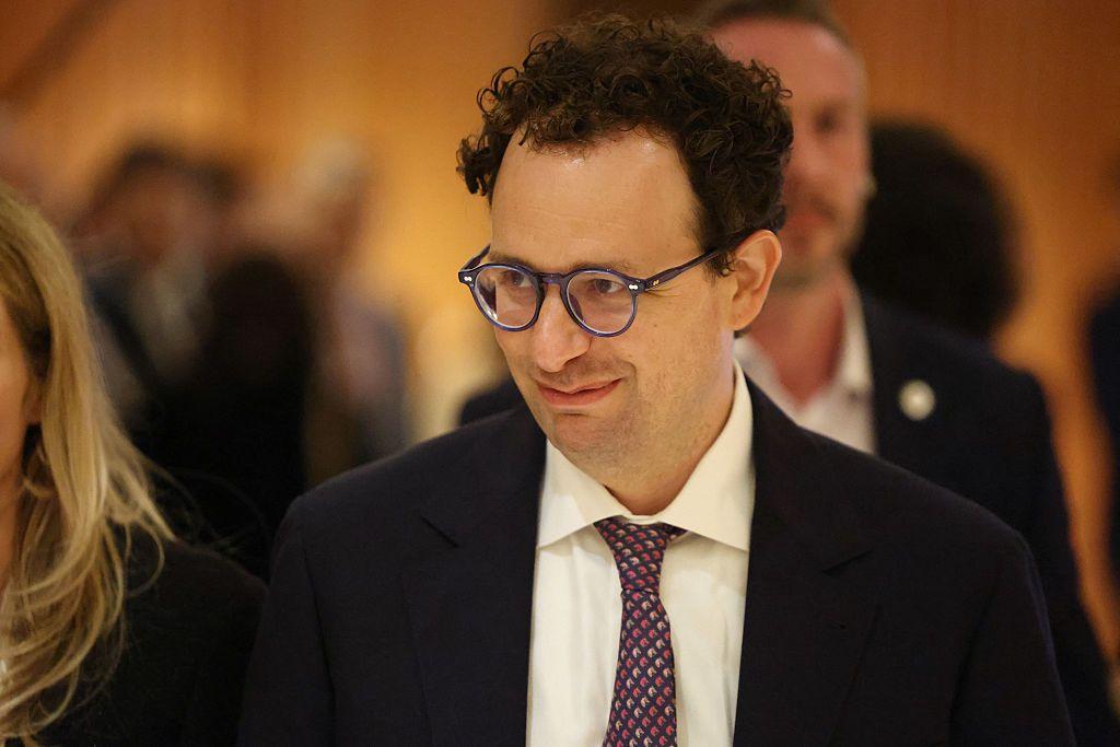 Un sonriente Dario Amodei, con lentes, traje oscuro y corbata, acude a una reunión con el presidente francés, Emmanuel Macron.