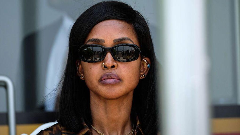 Primer plano de la princesa Ruth Komuntale con el pelo liso y negro, gafas de sol oscuras y varias joyas, entre ellas pendientes, un aro en la nariz y un collar. 
