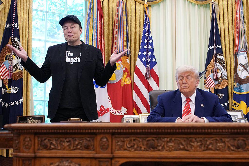 Elon Musk, director ejecutivo de Tesla, habla con periodistas junto al presidente estadounidense Donald Trump en el Despacho Oval de la Casa Blanca el 30 de mayo de 2025 en Washington. Trump está sentado en su oficina mirando hacia abajo, mientras que Musk sonríe a la cámara con una expresión de sorpresa. 