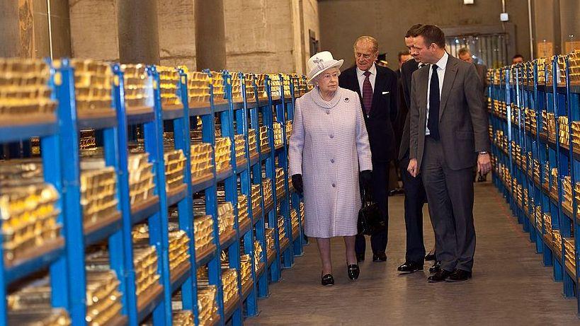 La reina Isabel II vestida de violeta observa pilas de lingotes de oro durante su visita al Banco de Inglaterra junto al príncipe Felipe, duque de Edimburgo