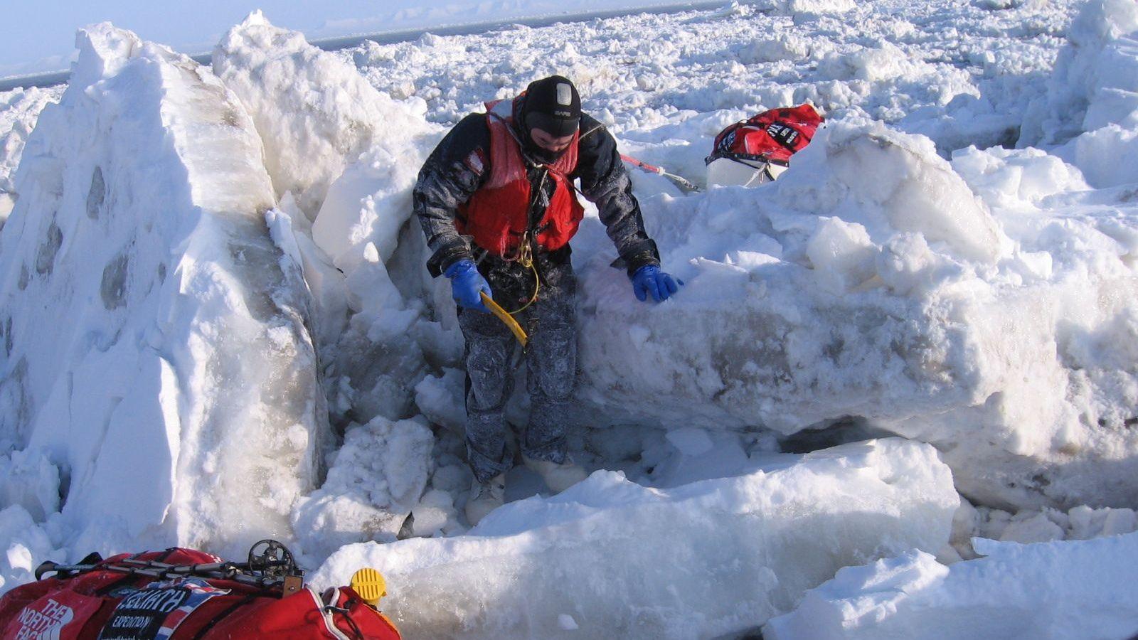 Un hombre, ataviado con ropa de abrigo para climas extremadamente fríos y portando un piolet, trepa por la banquisa en el estrecho de Bering.