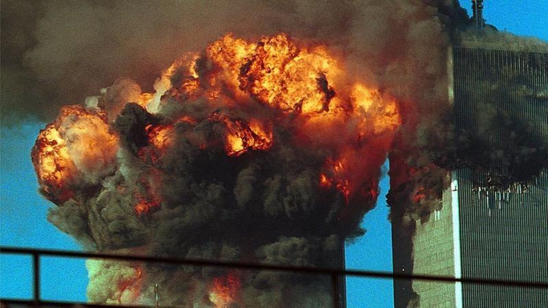 La parte superior de una de las Torres Gemelas en llamas mientras que de la otra, en su parte superior, sale humo negro