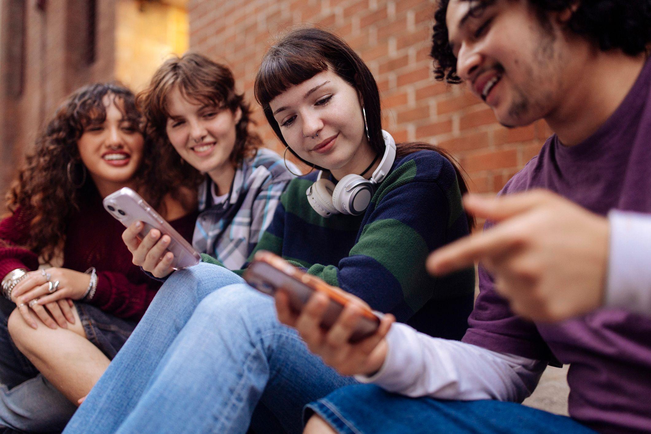 Varios jóvenes sonriendo mirando celulares