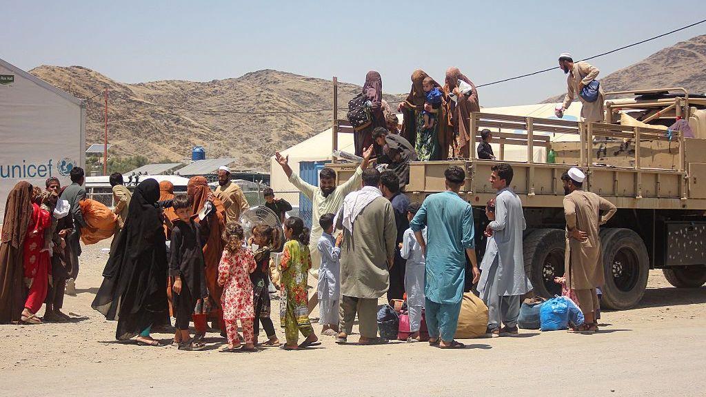 Esta fotografía, tomada el 24 de junio de 2026, muestra a afganos retornados, deportados de Pakistán, bajando de un camión militar a su llegada al campamento de Omari, cerca del puesto fronterizo entre Afganistán y Pakistán en Torkham, provincia de Nangarhar. 