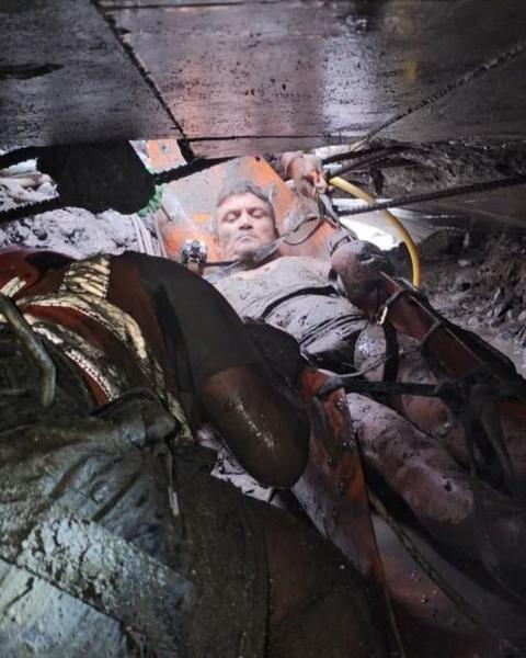 Un hombre con el cuerpo lleno de lodo al momento de ser sacado del interior del túnel. Está sobre una especie de camilla