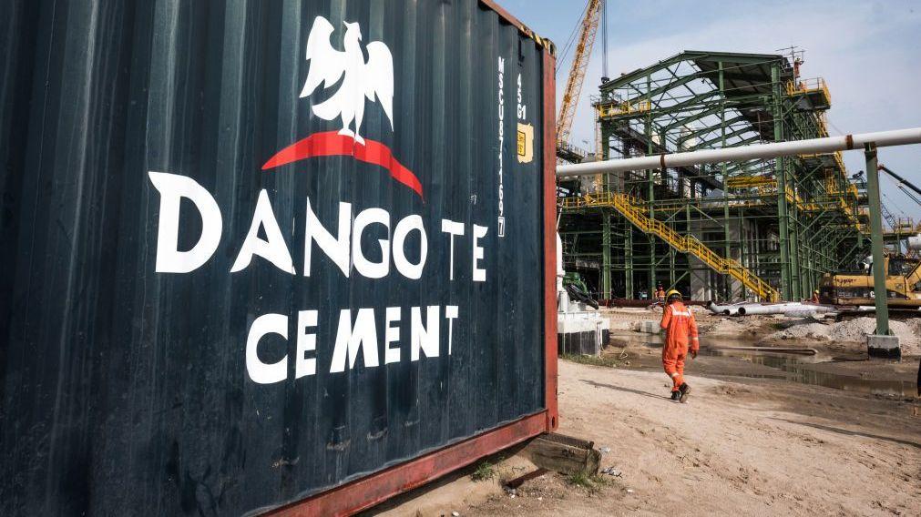 El logotipo de Dangote Cement S.A. se encuentra sobre una barrera en el emplazamiento de la refinería de petróleo y la planta de fertilizantes de Dangote Industries Ltd, actualmente en construcción en el distrito de Ibeju Lekki, en las afueras de Lagos, Nigeria.