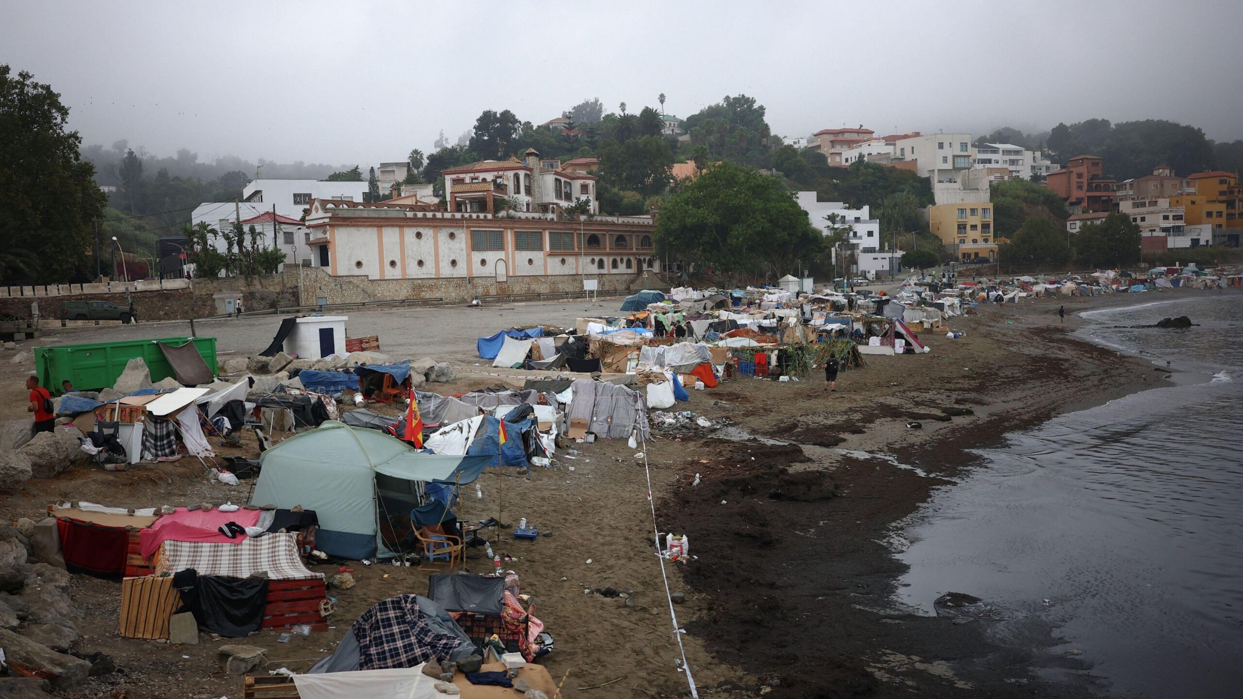 Tiendas de campaña a lo largo de la playa Trampolín en Ceuta en un día nublado.