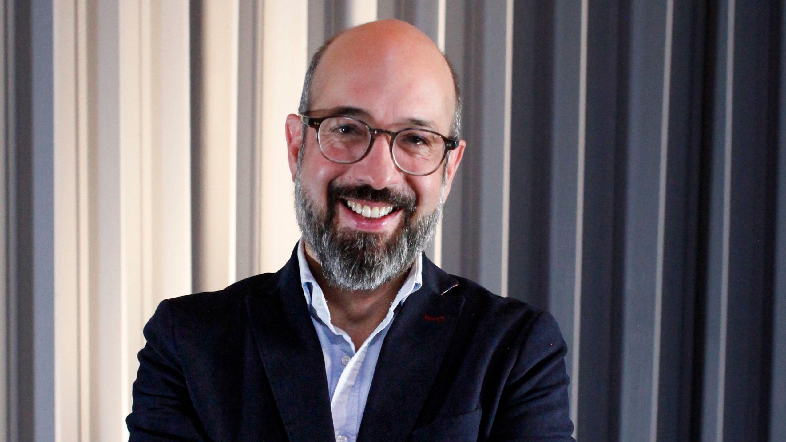 Pedro Salazar, autor de Totalitarismo Total. Lleva una camisa azul y una chaqueta azul marino. Lentes y sonríe a la cámara. 
