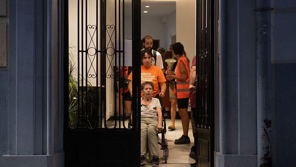 Maricarmen, en silla de ruedas, es ayudada a salir de su casa por sus simpatizantes. 