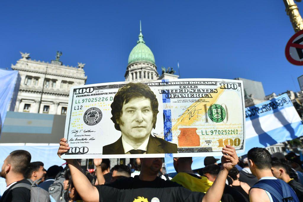 Partidario de Milei con un cartel donde se ve un dólar y la cara del presidente.