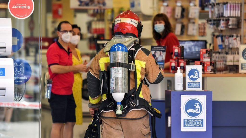 Un bombero de Cataluña conversa con los empleados de una tienda de electrodomésticos sobre una posible fuga de gas.
