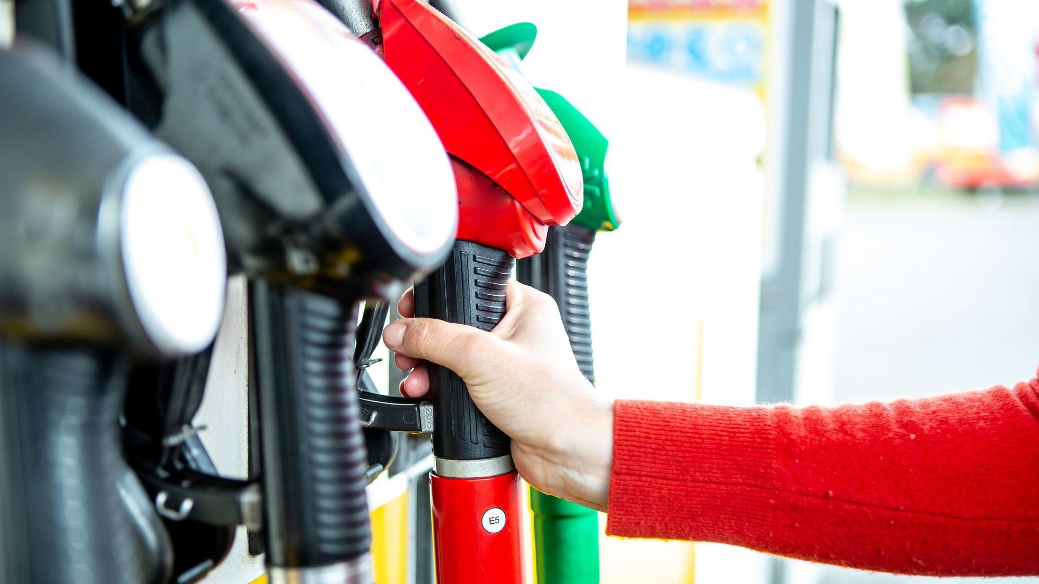 Mano sosteniendo una manguera de una bomba de gasolina. 