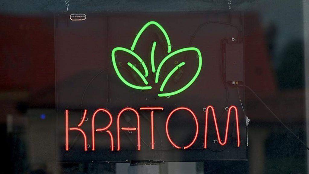 Cartel luminoso en una tienda que dice Kratom y tiene el dibujo de unas hojas verdes.