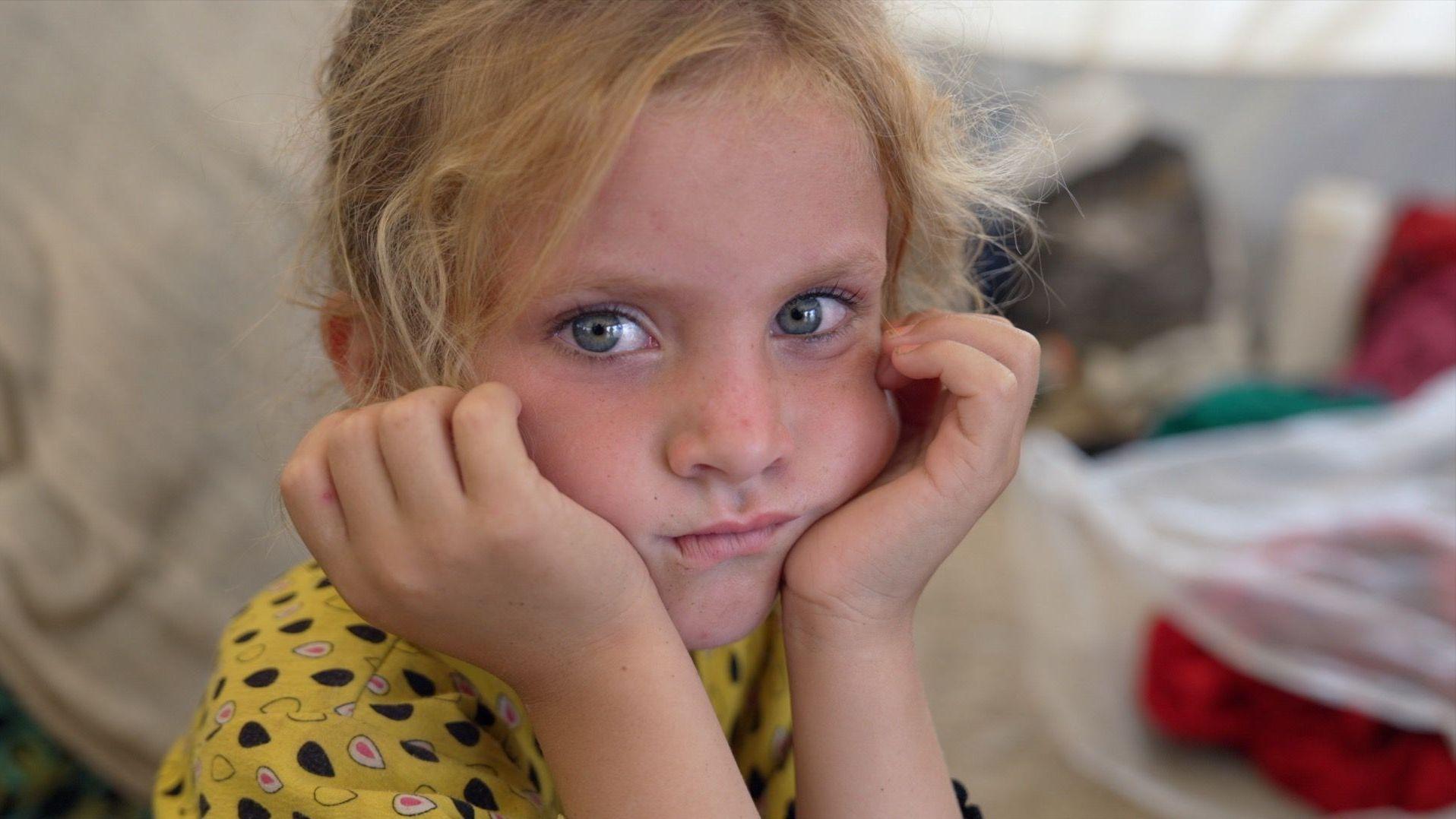 Una niña vestida con un atuendo amarillo mira fijamente a la cámara.