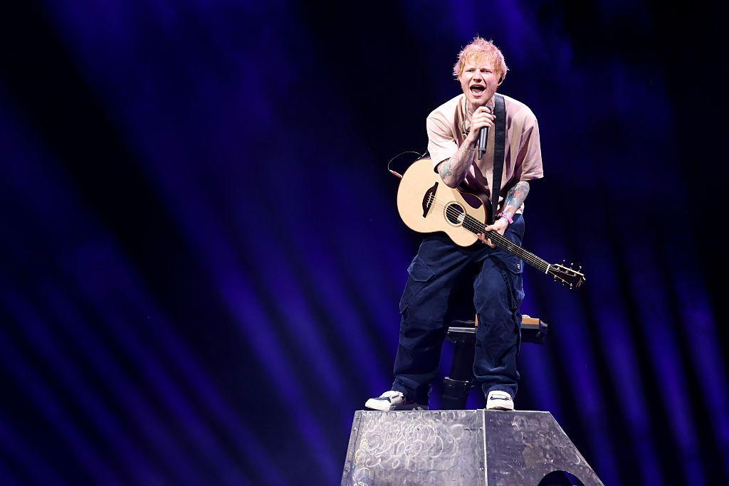 Ed Sheeran con una guitarra canta sobre un escenario. 