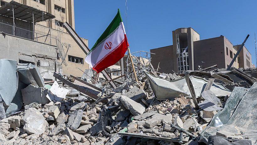 Una bandera iraní ondea entre los escombros de una comisaría de policía, dañada por ataques aéreos el día anterior, el 3 de marzo de 2026, en Teherán, Irán.