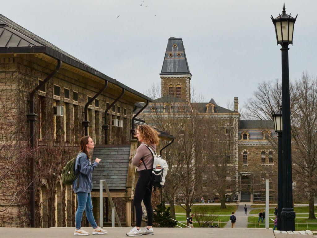 Dos estudiantes charlando frente a edificios de la Universidad de Cornell
