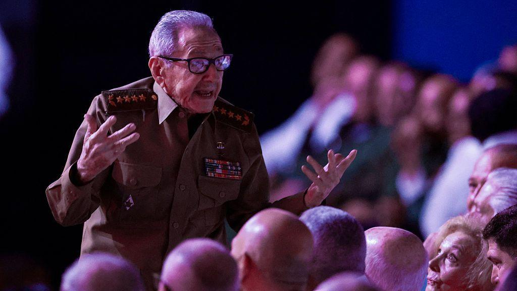 Raúl castro da un discurso vestido con un uniforme militar. Una multitud de personas lo observa con atención. 