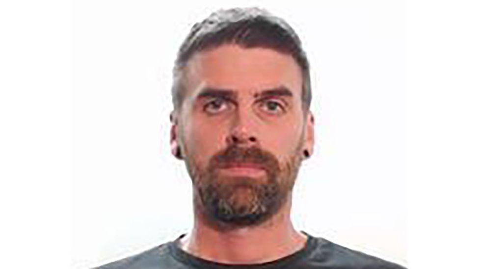 Foto policial de Christopher Malcolm, un hombre con barba que mira a la cámara.