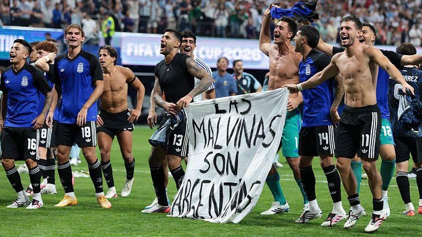 Jugadores argentinos exhiben una pancarta que dice "Las Malvinas son argentinas" tras su victoria sobre Inglaterra en el Mundial de fútbol en Atlanta, Estados Unidos, julio de 2026. 