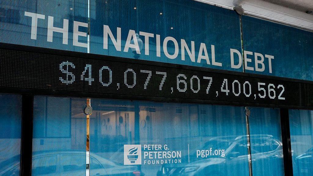 Una pantalla muestra un monto superior a los 40 billones de dólares bajo el título "La deuda nacional" en inglés.