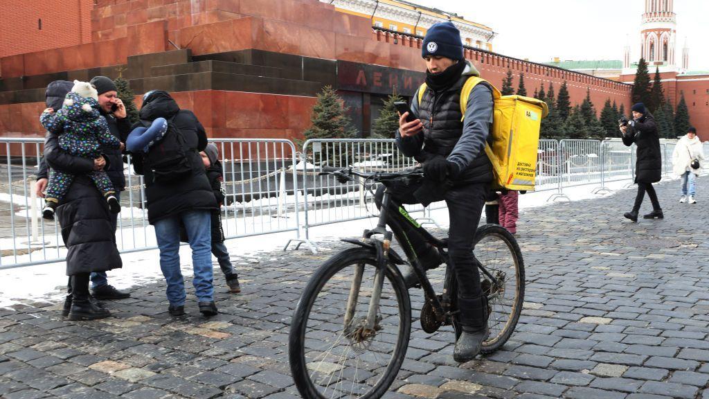 Un repartidor de comida de Yandex Eats cruza la Plaza Roja en bicicleta