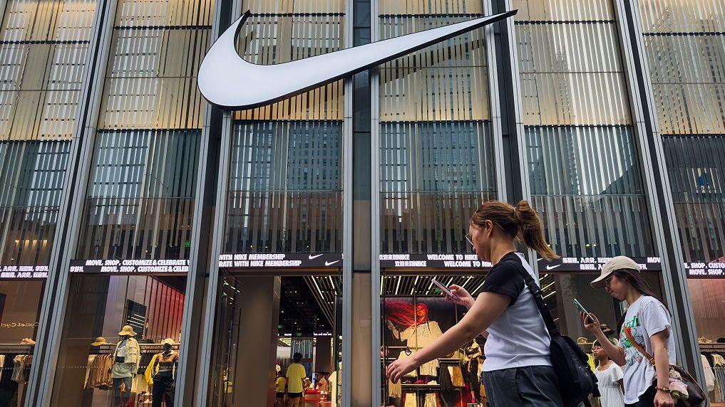 El 12 de abril de 2025 en Shenzhen, China, se observa a peatones caminando frente a una tienda Nike con un logotipo en exhibición. 