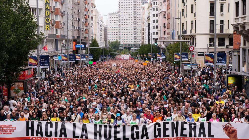 Una gran multitud ocupa toda una amplia avenida en Madrid. La gente que está al frente sostiene un gran cartel que dice "Hacia la huelga general".