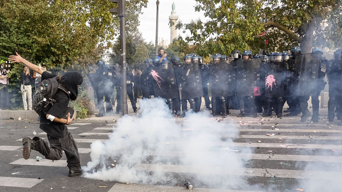 Un manifestante patea una lata de gas lacrimógeno mientras la policía observa durante los disturbios en París el 6 de octubre.