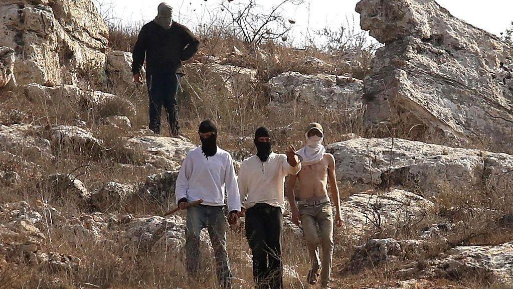 Colonos judíos, con los rostros cubiertos, aparecen en una imagen durante un presunto ataque contra agricultores palestinos, periodistas y activistas extranjeros en Nablus, en Cisjordania, el 8 de noviembre de 2025. 