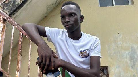 Un joven con una camiseta blanca está apoyado en la barandilla oxidada de un tramo de escaleras