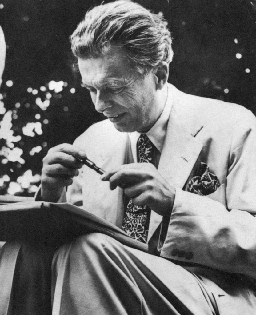 Aldous Huxley, con traje y un lapicero en la mano.