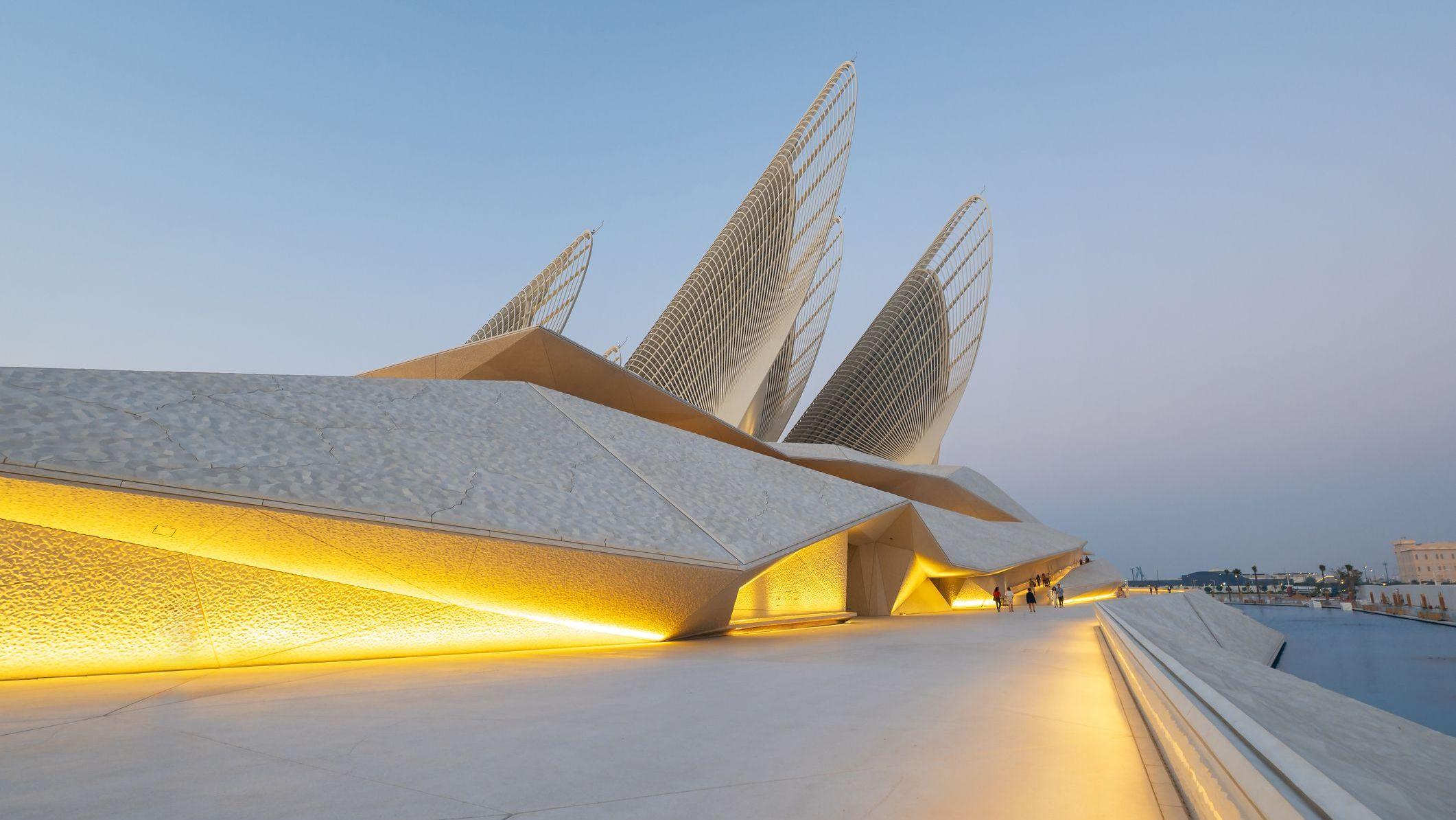 La fachada del Museo Nacional Zayed, a orillas del mar, con unas tiras de luz cálida encendidas.