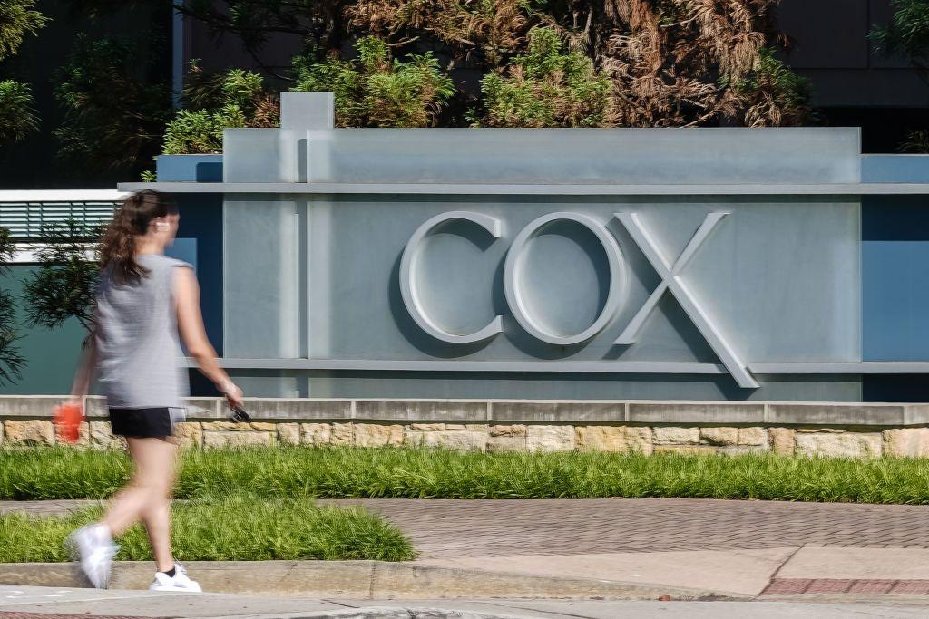 Una mujer pasa frente al lema de la compañía Cox en su sede de Atlanta, Georgia. 