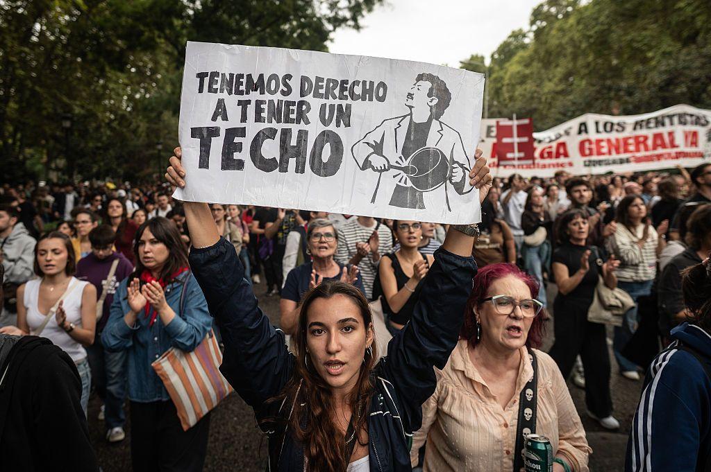 Una mujer porta con cartel en el que se lee: tenemos derecho a un techo.