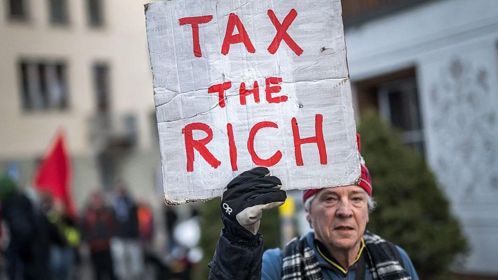 El británico Phil White, de Patriotic Millionaires, sostiene un cartel con la consigna “Tax the Rich” (“Gravar a los ricos”) durante una protesta contra el Foro Económico Mundial (WEF), antes de su reunión anual en Davos, el 19 de enero de 2025.