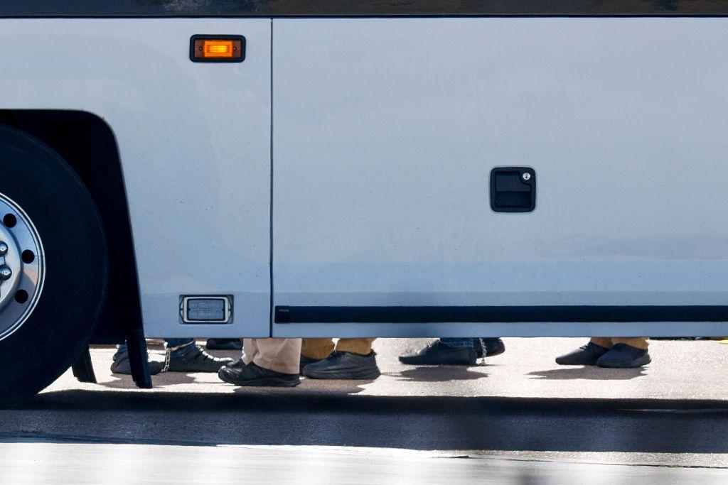 Detrás de un autobús se adivina a migrantes con cadenas en los pies antes de abordar un vuelo de Eastern Air Express en Dallas Love Field para ser deportados el martes 28 de julio de 2026, en Dallas, Texas, Estados Unidos. (Elías Valverde II/The Dallas Morning News vía Getty Images)