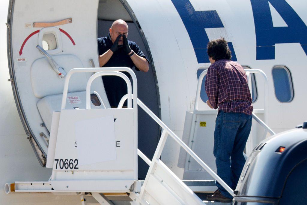 Un hombre llama a alguien que está en la pista mientras un hombre esposado aborda un avión de Eastern Air Express en Dallas Love Field el martes 28 de julio de 2026, en Dallas. (Elías Valverde II/The Dallas Morning News vía Getty Images)
