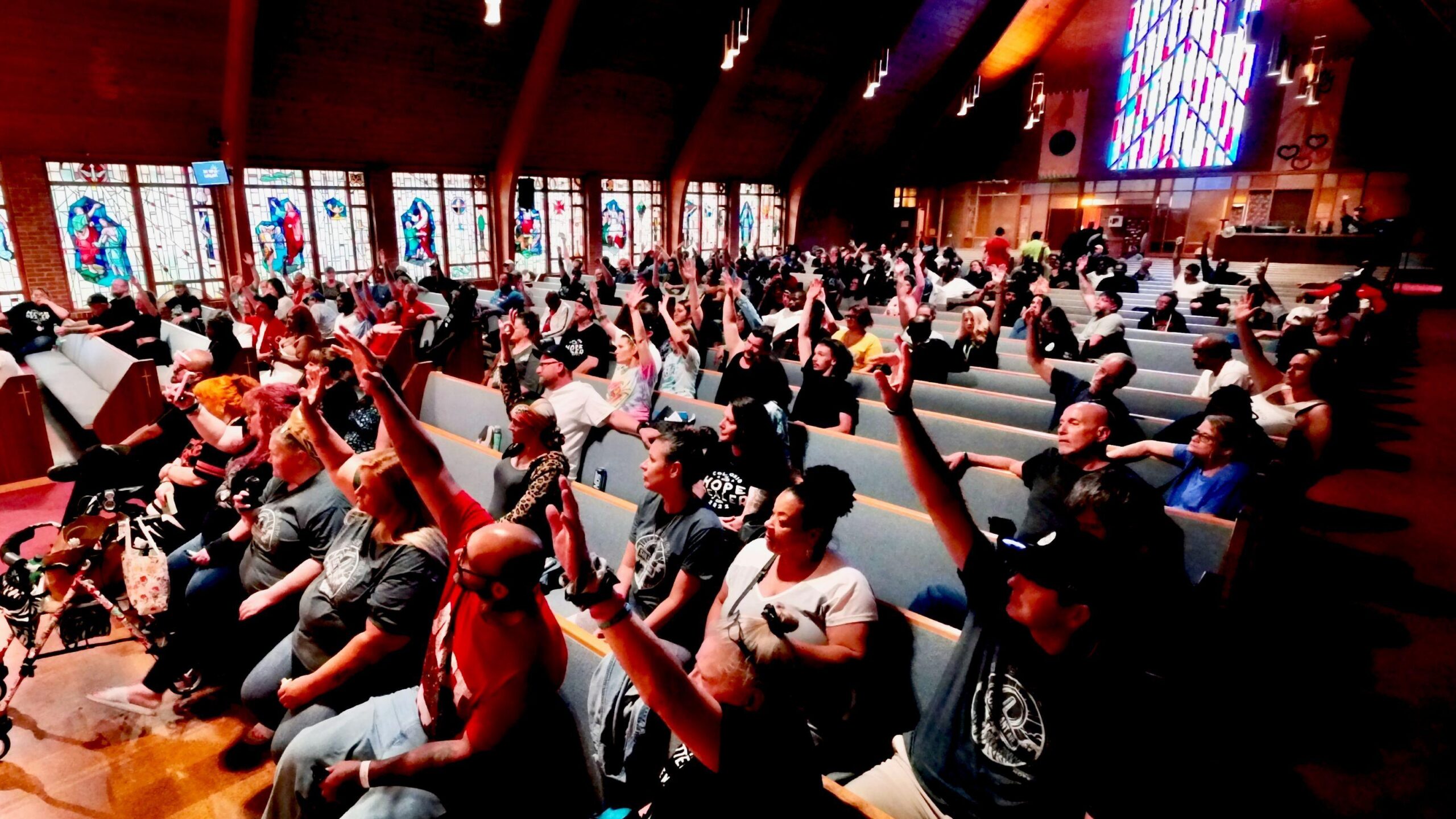 Miembros de Hope Dealer Community, un grupo de rehabilitación, se sientan en filas de bancos para una reunión semanal en la iglesia Glenwood.