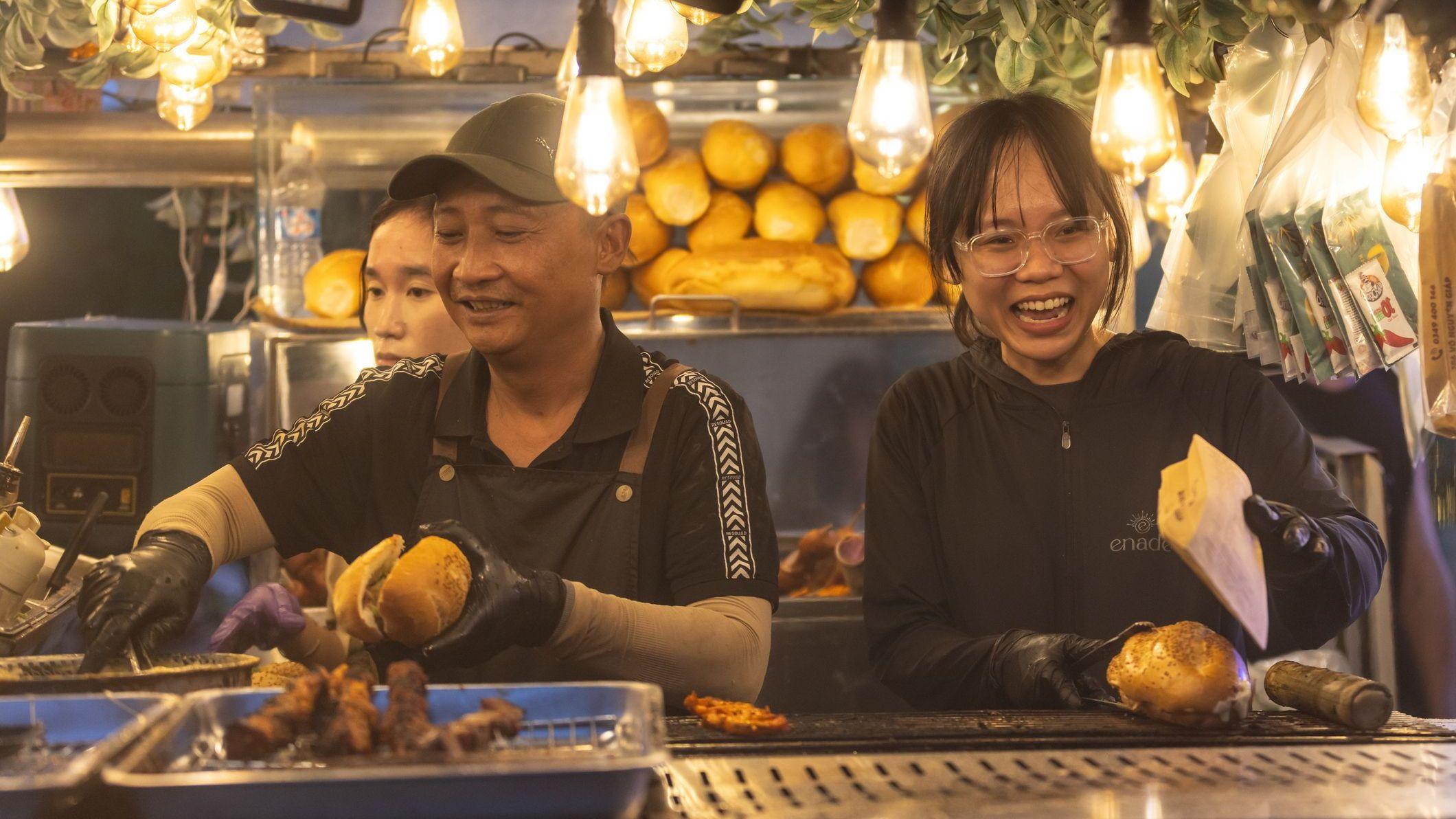 Tres personas trabajando en un puesto de sándwiches en Ciudad Ho Chi Minh.